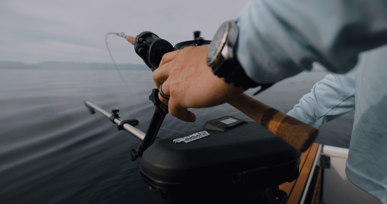 Fisherman actively using his rod and reel positioned in the rod holder mounted on the Scotty High Performance downrigger model.